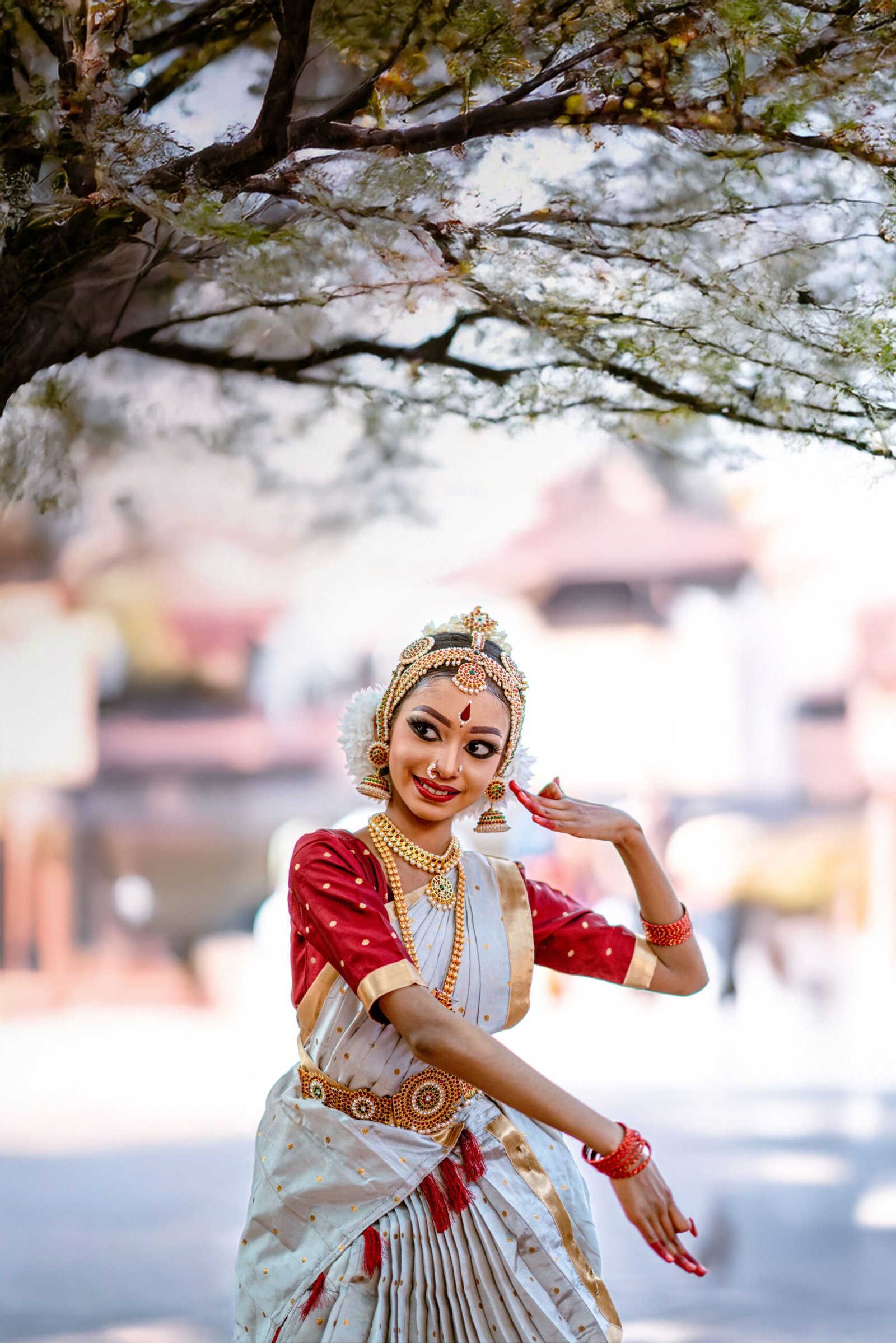 Traditional Indian dancer in vibrant costume under a blossoming tree in Kerala.